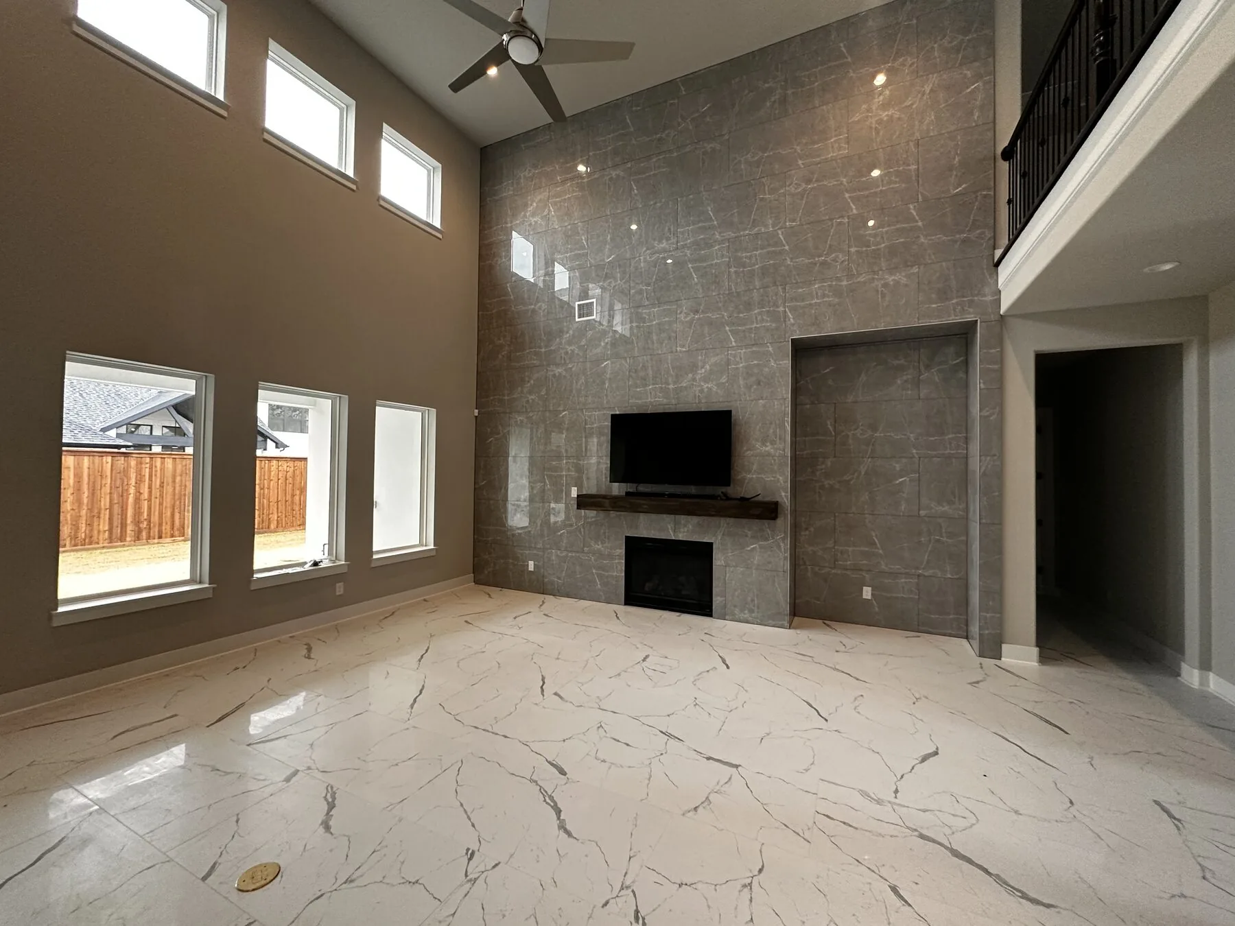 Two-story great room with full-height porcelain slab feature wall, fireplace surround, and built-in display alcove — Frisco, Dallas TX
