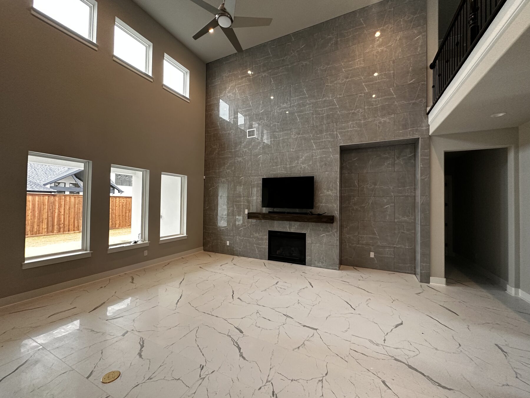 Two-story great room with full-height porcelain slab feature wall, fireplace surround, and built-in display alcove — Frisco, Dallas TX