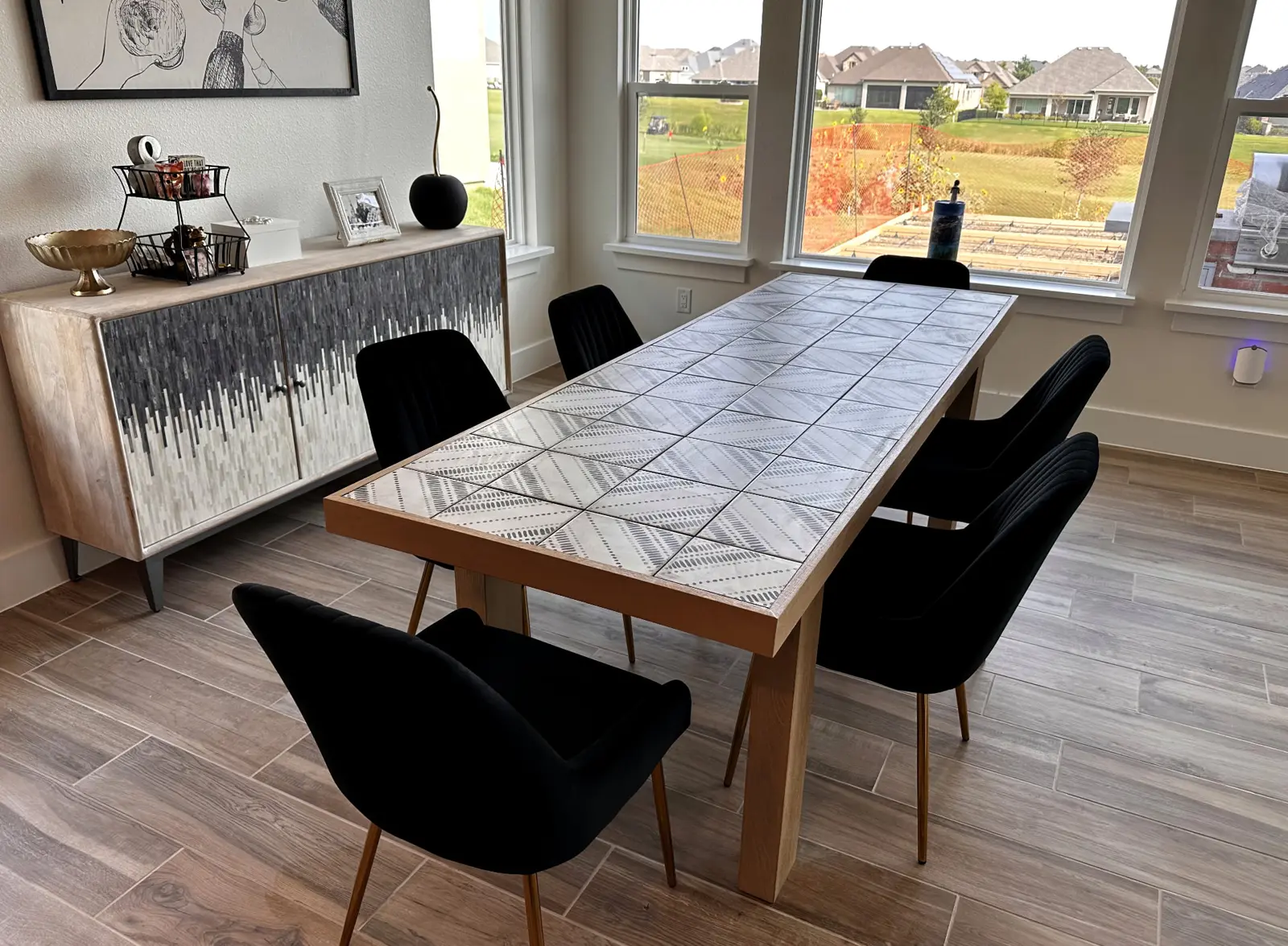 Wood-look plank tile flooring installed in a Dallas dining room with a tiled-top table and black velvet chairs