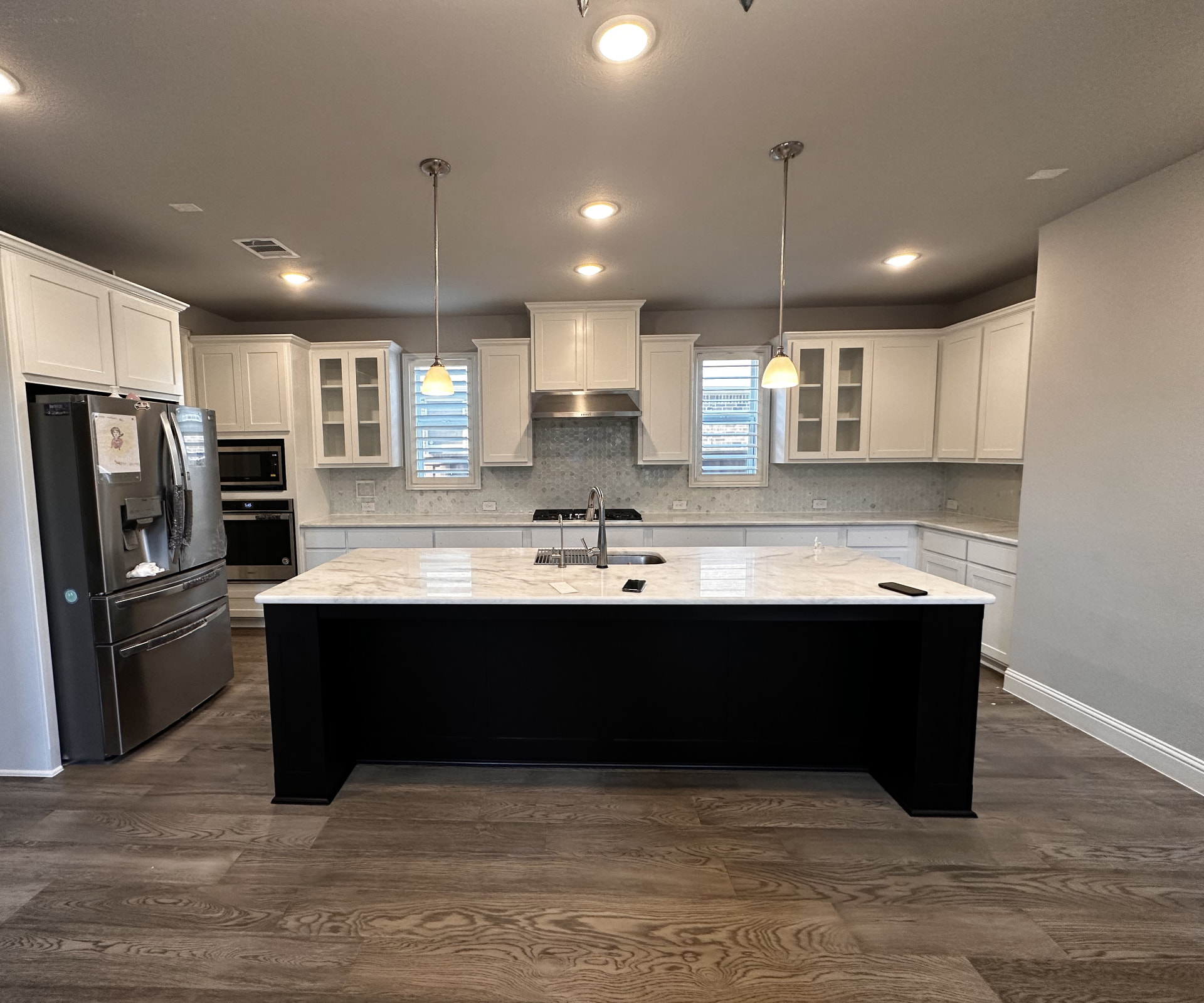 Classic white kitchen with oversized black island, waterfall-edge quartz, and glass-front upper cabinets — Plano, Dallas TX